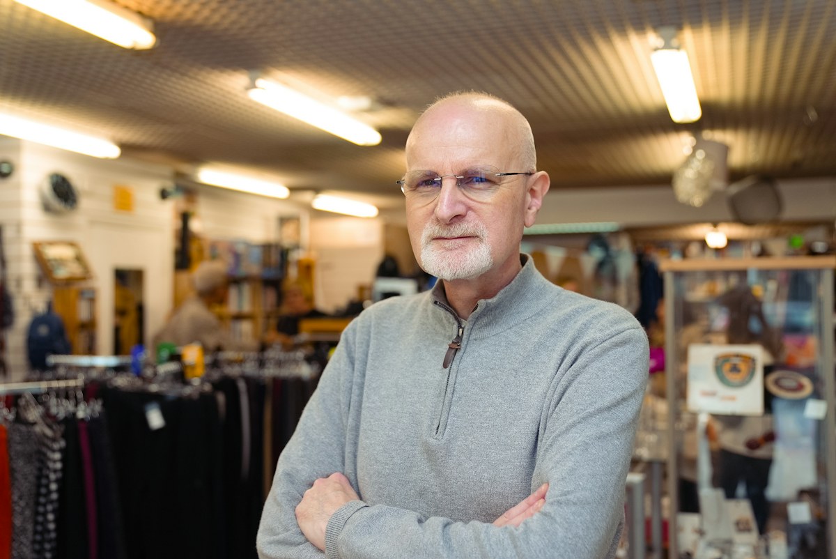 An older adult wearing glasses and a checked shirt in a shop